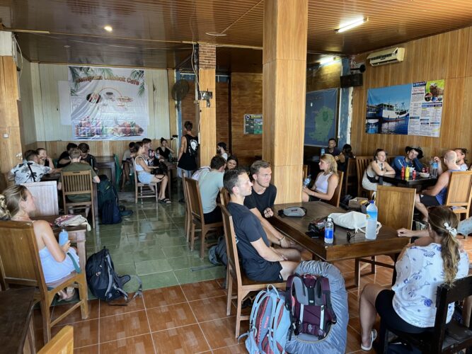 Travellers gather at the Cempaka Lombok Cafe. A wall poster advertises the Komodo cruise